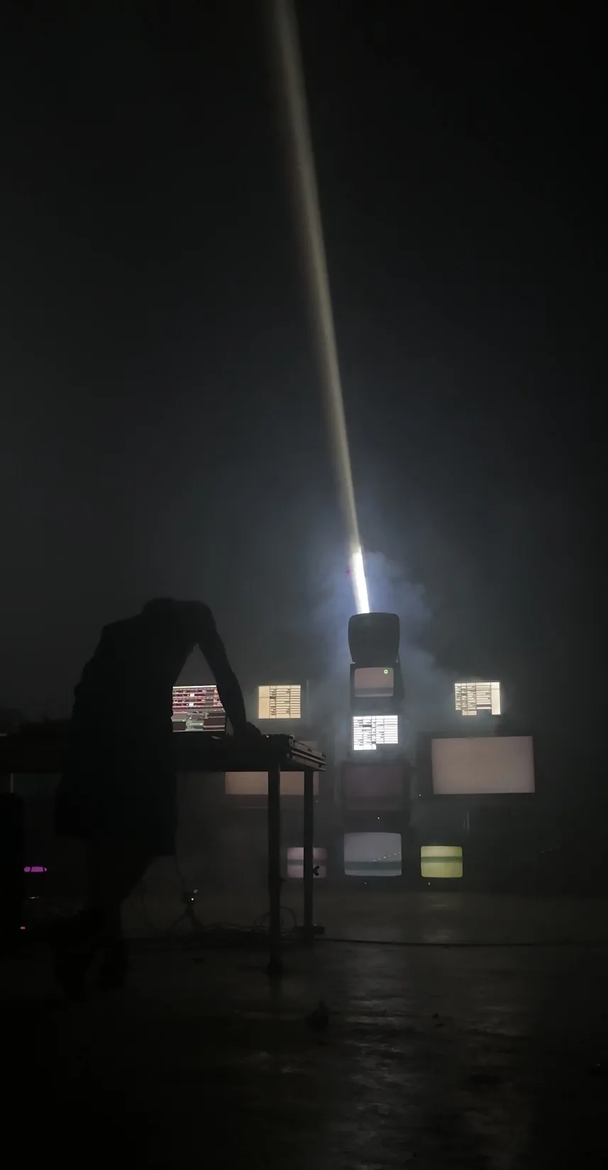 Silueta frente a monitores y un haz de luz en una instalación audiovisual